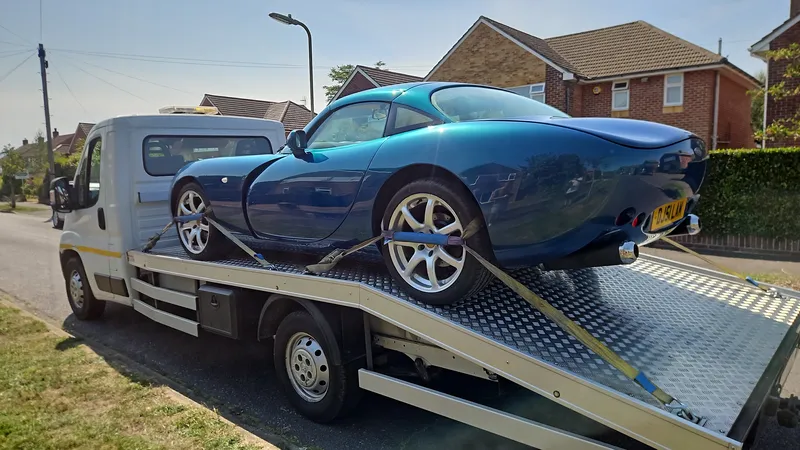 Blue TVR sports car carefully transported on flatbed by MotorMoves in residential UK street