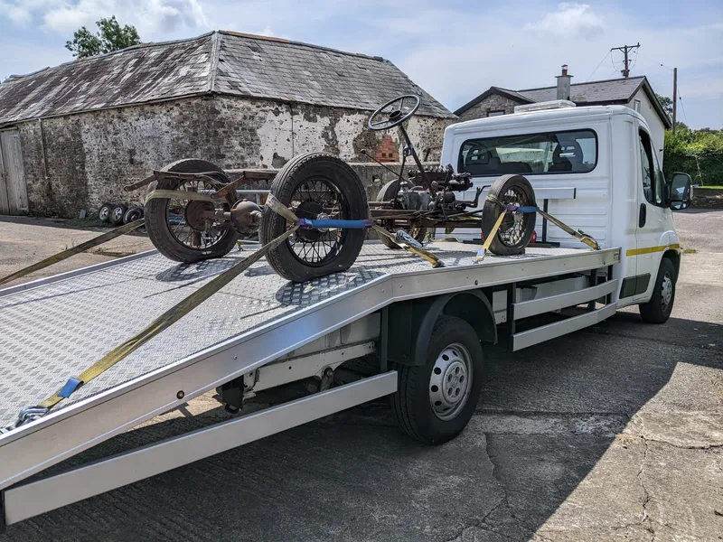 Vintage vehicle chassis secured on MotorMoves flatbed transporter for safe UK collection and delivery